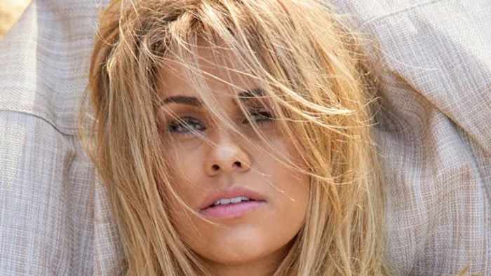 Paige VanZant sports her blonde hair in a messy down-do and stares at the camera.